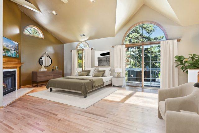 8252 N Caldwell Ave, Niles, IL 60714 - bedroom featuring high vaulted ceiling, access to exterior, a glass covered fireplace, and wood finished floors