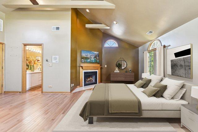 8252 N Caldwell Ave, Niles, IL 60714 - bedroom featuring high vaulted ceiling, a fireplace with flush hearth, light wood-style flooring, baseboards, and connected bathroom