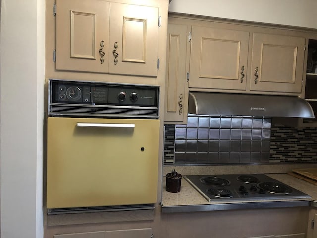 6100 S Parkside Ave, Chicago, IL 60638 - kitchen featuring oven, under cabinet range hood, electric cooktop, and decorative backsplash