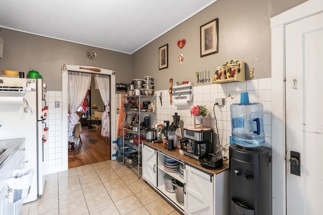 4109 W Oakdale Ave, Chicago, IL 60641 - kitchen with light tile patterned floors, tile walls, white cabinets, and freestanding refrigerator