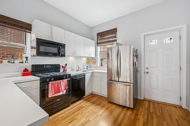 3430 S Parnell Ave, Chicago, IL 60616 - kitchen featuring black appliances, light countertops, white cabinets, a sink, and light wood-style flooring