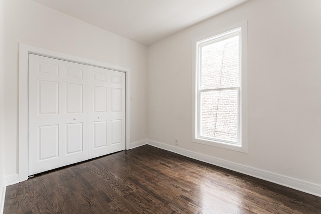 3216 W Walnut St, Chicago, IL 60624 - unfurnished bedroom featuring multiple windows, dark wood-style floors, baseboards, and a closet