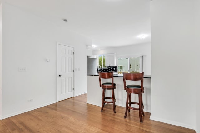 1544 Sauganash Ct, Gurnee, IL 60031 - kitchen featuring white cabinetry, wood finished floors, a breakfast bar area, dark countertops, and a peninsula
