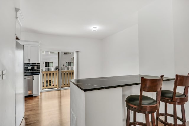 1544 Sauganash Ct, Gurnee, IL 60031 - kitchen with dark countertops, a peninsula, white cabinetry, and a breakfast bar