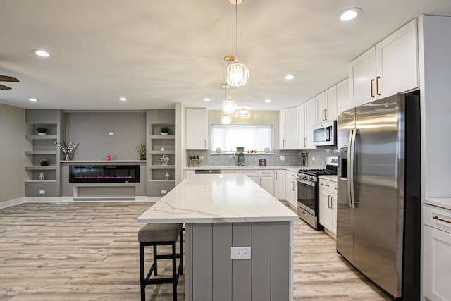 8040 S Lafayette Ave, Chicago, IL 60620 - kitchen with stainless steel appliances, a kitchen island, light wood-style flooring, white cabinetry, and a breakfast bar area
