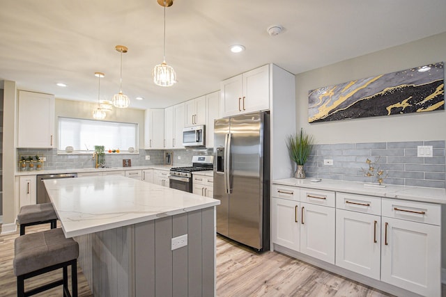 8040 S Lafayette Ave, Chicago, IL 60620 - kitchen with appliances with stainless steel finishes, decorative backsplash, a kitchen bar, white cabinetry, and a kitchen island