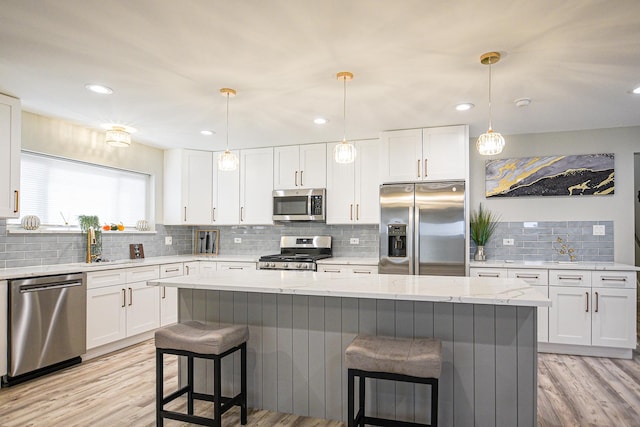 8040 S Lafayette Ave, Chicago, IL 60620 - kitchen featuring stainless steel appliances, decorative backsplash, a breakfast bar, light wood finished floors, and white cabinetry