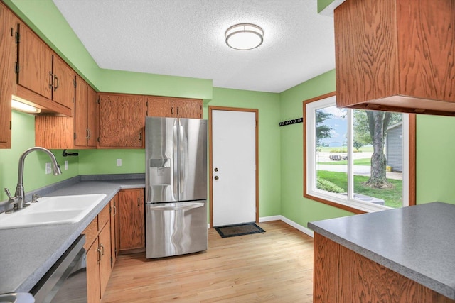 907 S Trailside Dr, Mahomet, IL 61853 - kitchen with stainless steel fridge, dishwasher, light wood-style floors, brown cabinets, and a textured ceiling