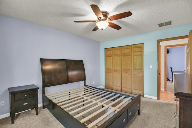 907 S Trailside Dr, Mahomet, IL 61853 - bedroom with light colored carpet, a closet, a textured ceiling, and a ceiling fan