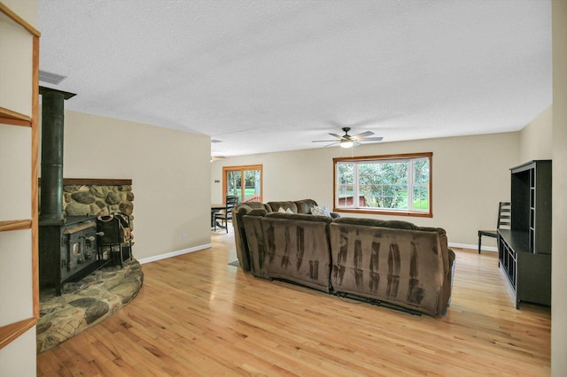 907 S Trailside Dr, Mahomet, IL 61853 - living room with ceiling fan, light wood-style flooring, a wood stove, and a textured ceiling