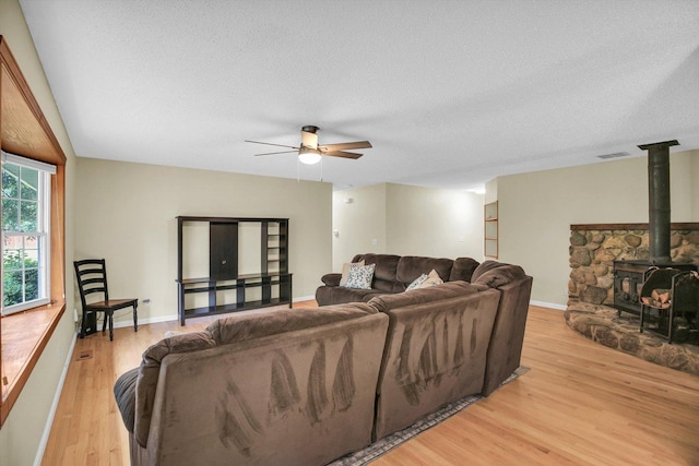 907 S Trailside Dr, Mahomet, IL 61853 - living room featuring light wood-style floors, a ceiling fan, a textured ceiling, and a wood stove