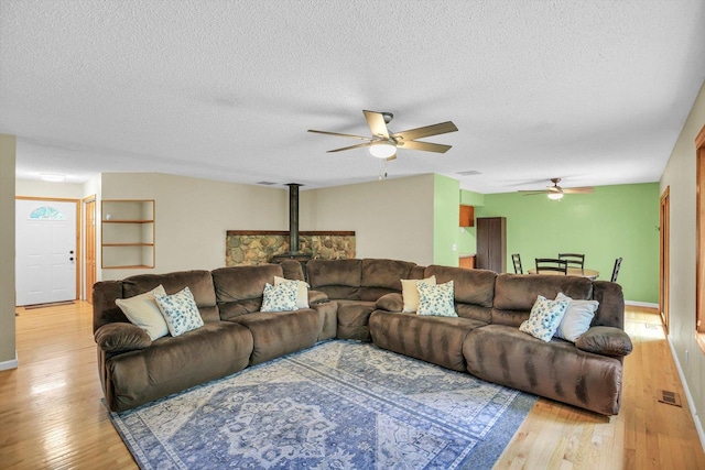 907 S Trailside Dr, Mahomet, IL 61853 - living area with ceiling fan, light wood-style floors, a textured ceiling, and a wood stove