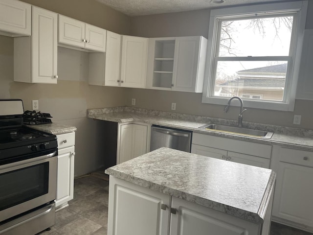 622 Clark St, Marseilles, IL 61341 - kitchen with stainless steel appliances, a sink, white cabinets, a kitchen island, and a textured ceiling