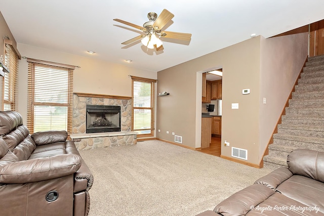 12401 Bigelow Ave, Hebron, IL 60034 - living area featuring light colored carpet, baseboards, a ceiling fan, a stone fireplace, and stairway