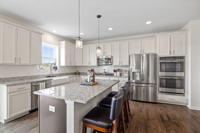 12414 Dublin Ln, Plainfield, IL 60585 - kitchen featuring appliances with stainless steel finishes, a sink, white cabinetry, a kitchen island, and recessed lighting