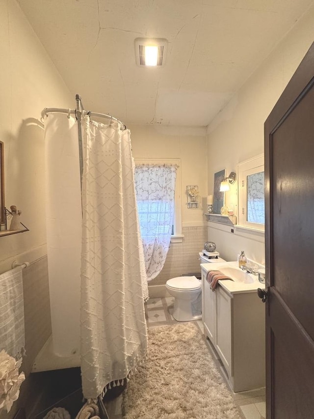 1118 W 4th St, Dixon, IL 61021 - bathroom with vanity, toilet, tile walls, a shower with curtain, and a wainscoted wall
