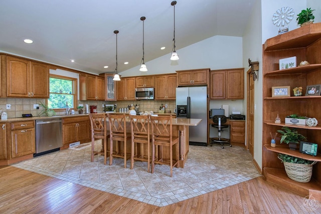 28671 Moose Range Rd, Sycamore, IL 60178 - kitchen featuring appliances with stainless steel finishes, brown cabinets, light wood finished floors, a kitchen bar, and a center island