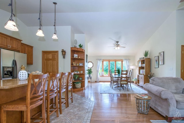 28671 Moose Range Rd, Sycamore, IL 60178 - kitchen featuring stainless steel fridge with ice dispenser, open floor plan, high vaulted ceiling, brown cabinets, and light stone countertops