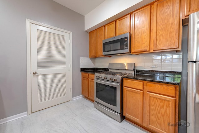 2142 W Madison St Unit 1, Chicago, IL 60612 - kitchen featuring appliances with stainless steel finishes, decorative backsplash, dark stone countertops, light marble finish flooring, and baseboards