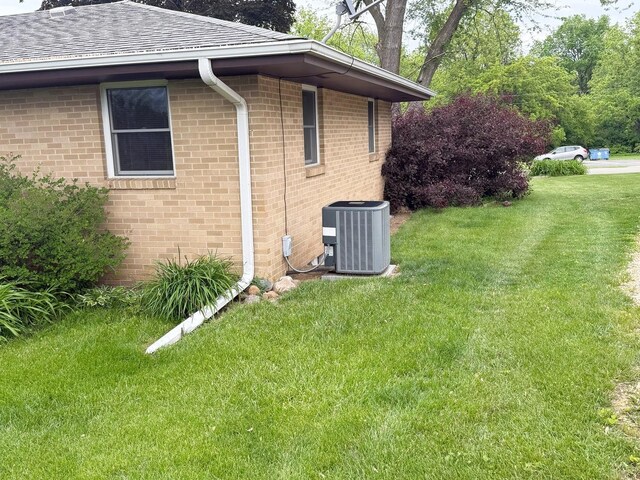 1417 S College Ave, Dixon, IL 61021 - view of side of property with central AC unit, brick siding, a lawn, and a shingled roof