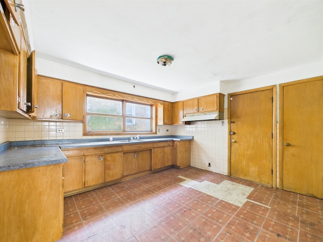 9216 S Ada St, Chicago, IL 60620 - kitchen with under cabinet range hood, brown cabinets, a sink, and decorative backsplash