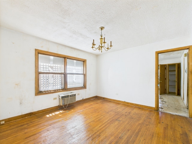 9216 S Ada St, Chicago, IL 60620 - unfurnished room with a wall mounted air conditioner, a chandelier, wood-type flooring, baseboards, and a textured ceiling