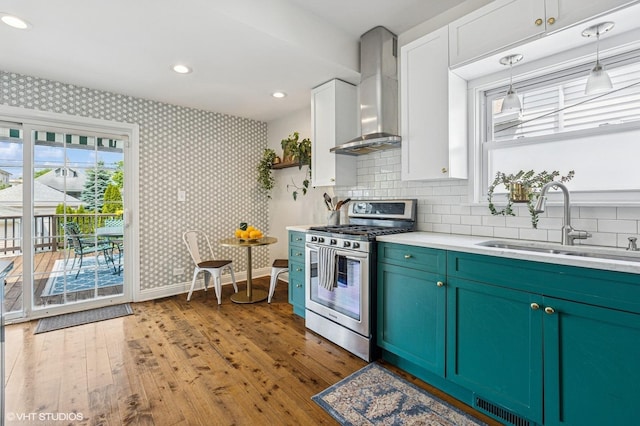 4058 N Kostner Ave, Chicago, IL 60641 - kitchen featuring gas stove, a sink, wall chimney exhaust hood, wood finished floors, and wallpapered walls