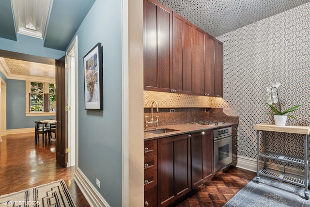 1350 N State Pkwy Unit Gs, Chicago, IL 60610 - kitchen featuring stainless steel oven, baseboards, a sink, wallpapered walls, and dark stone counters