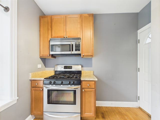 2609 W Rosemont Ave Unit C, Chicago, IL 60659 - kitchen with stainless steel appliances, baseboards, plenty of natural light, and light wood-style floors
