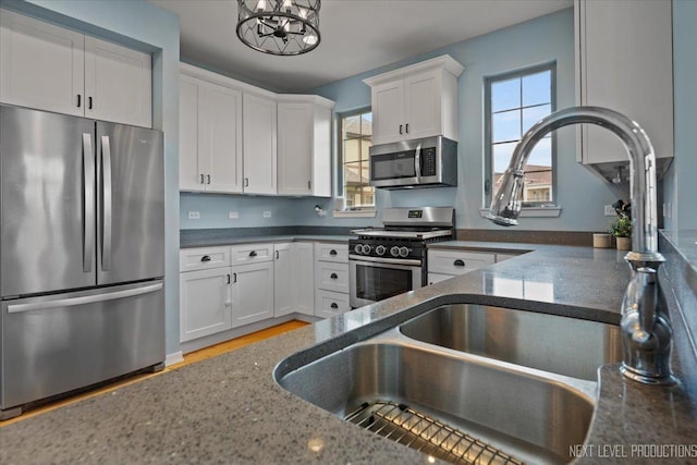 12709 Wild Rye Ct, Plainfield, IL 60585 - kitchen featuring stainless steel appliances, white cabinetry, dark stone countertops, a chandelier, and light wood-style flooring
