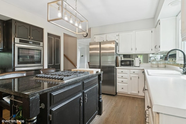 904 Warwick Ln, Lake Zurich, IL 60047 - kitchen with appliances with stainless steel finishes, white cabinetry, dark cabinetry, light wood finished floors, and decorative light fixtures