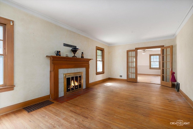 1044 Garfield Ave, Aurora, IL 60506 - unfurnished living room with light wood-type flooring, french doors, a tiled fireplace, ornamental molding, and ceiling fan