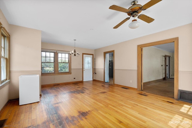 1044 Garfield Ave, Aurora, IL 60506 - unfurnished room featuring radiator heating unit, light wood-style floors, a chandelier, and a ceiling fan