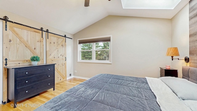 1176 Westport Rdg, Crystal Lake, IL 60014 - bedroom featuring a barn door, light wood-style floors, vaulted ceiling, a ceiling fan, and a skylight