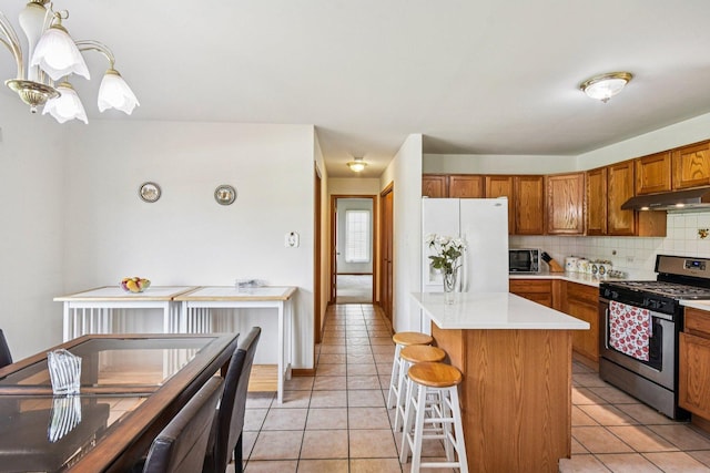 3410 Beckwith Ln, Crete, IL 60417 - kitchen featuring gas range, white refrigerator with ice dispenser, under cabinet range hood, brown cabinets, and light countertops