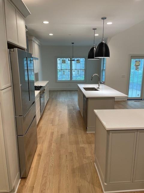 1672 Huntington Ln, Highland Park, IL 60035 - kitchen with a sink, an island with sink, light wood-type flooring, stainless steel appliances, and light countertops