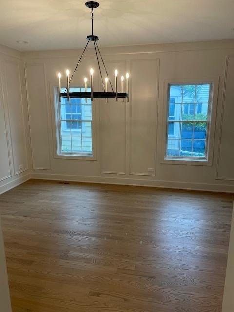 1672 Huntington Ln, Highland Park, IL 60035 - unfurnished dining area with a decorative wall, a chandelier, and wood finished floors