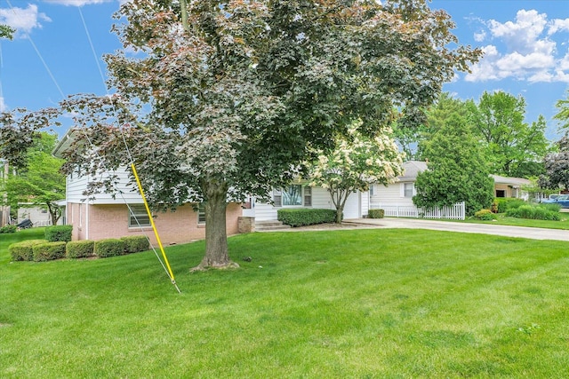 404 Maple Ln, Monticello, IL 61856 - view of property hidden behind natural elements featuring driveway, an attached garage, a front yard, and brick siding