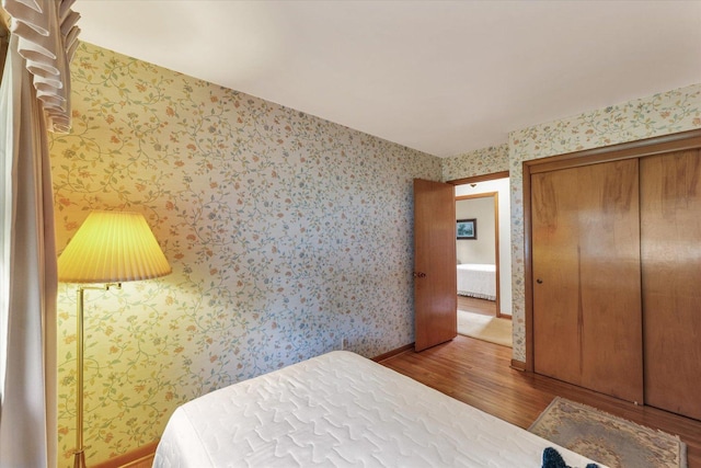 404 Maple Ln, Monticello, IL 61856 - bedroom with wood finished floors, wallpapered walls, baseboards, and a closet