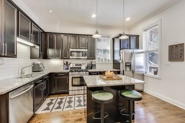 1908 N Whipple St Unit 2, Chicago, IL 60647 - kitchen with appliances with stainless steel finishes, a center island, crown molding, light wood-style floors, and decorative backsplash