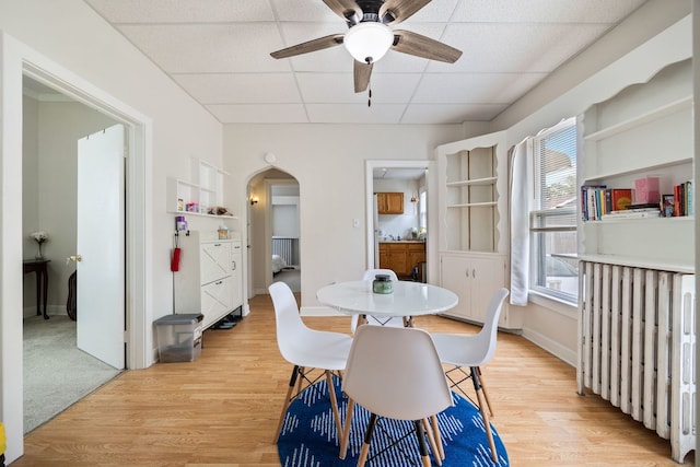 572 Walnut Ave, Elgin, IL 60123 - dining area with arched walkways, a paneled ceiling, a ceiling fan, light wood-type flooring, and baseboards