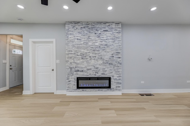 5731 S Damen Ave, Chicago, IL 60636 - unfurnished living room with wood finished floors, a stone fireplace, baseboards, and recessed lighting