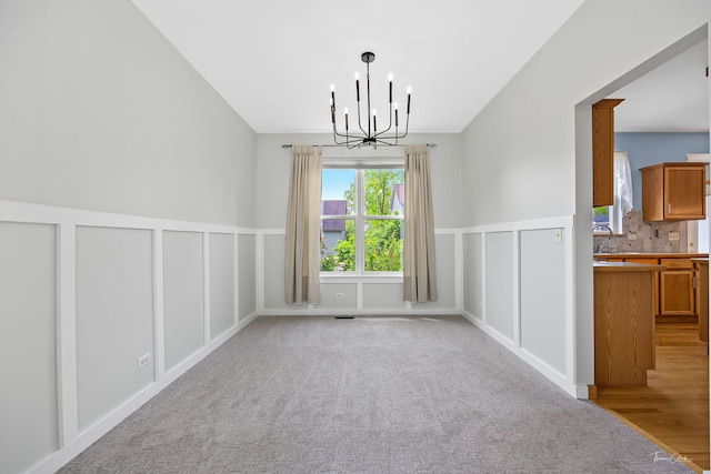 3151 Sawgrass Dr, Aurora, IL 60502 - unfurnished dining area featuring a chandelier, a decorative wall, vaulted ceiling, a wainscoted wall, and light colored carpet