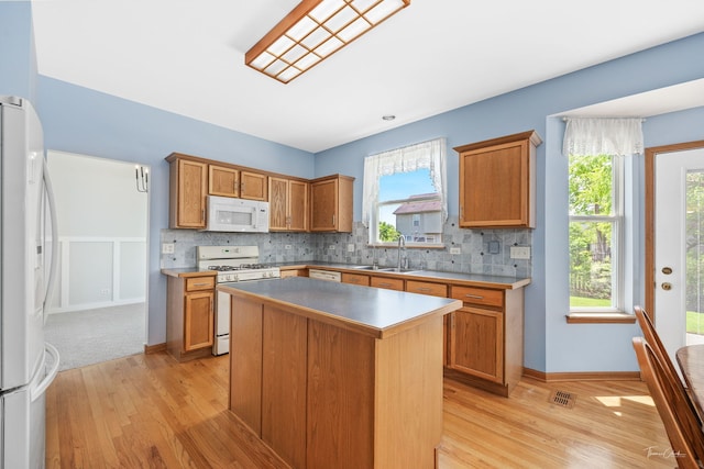3151 Sawgrass Dr, Aurora, IL 60502 - kitchen featuring white appliances, a sink, light wood-style floors, tasteful backsplash, and a kitchen island