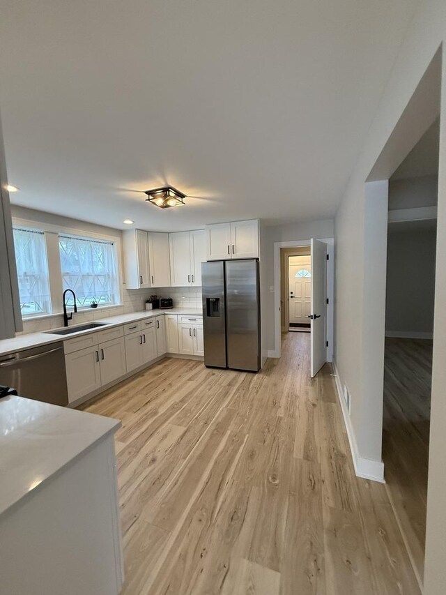 5301 S Mcvicker Ave, Chicago, IL 60638 - kitchen featuring appliances with stainless steel finishes, a sink, light wood-style flooring, white cabinetry, and light countertops