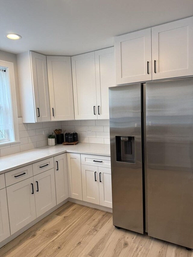 5301 S Mcvicker Ave, Chicago, IL 60638 - kitchen featuring stainless steel fridge with ice dispenser, light wood finished floors, light countertops, white cabinetry, and backsplash