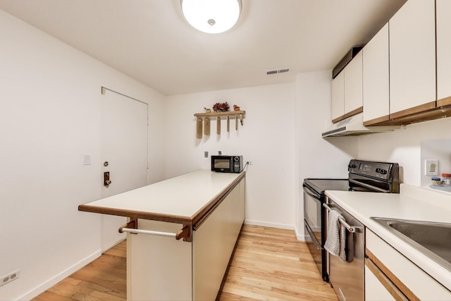 900 W Ainslie St Unit A, Chicago, IL 60640 - kitchen featuring black appliances, a peninsula, light wood-style flooring, and under cabinet range hood