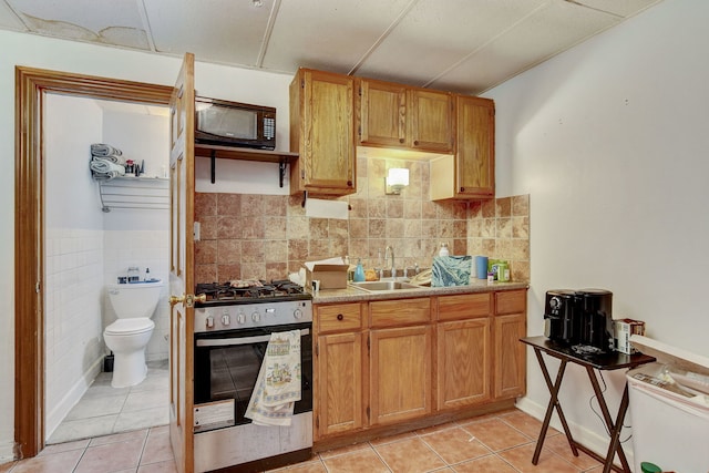 3342 S Aberdeen St, Chicago, IL 60608 - kitchen featuring stainless steel gas range oven, black microwave, a sink, light tile patterned flooring, and wainscoting