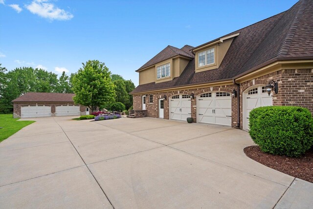 24355 S Arranmore Way, Frankfort, IL 60423 - view of home's exterior featuring brick siding, a garage, a shingled roof, stucco siding, and concrete driveway