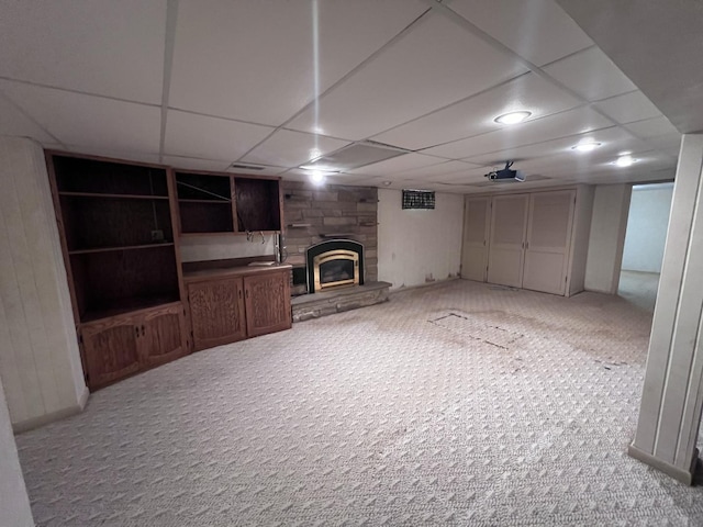 308 Tree Ln, Prophetstown, IL 61277 - unfurnished living room featuring a stone fireplace, light colored carpet, and a paneled ceiling
